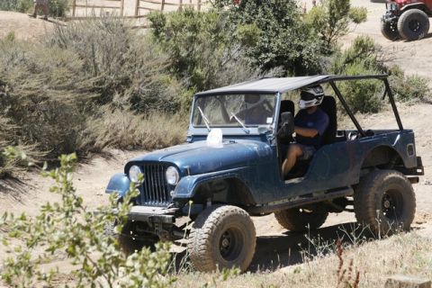 1989 Ford Bronco - A blue Jeep CJ-7 navigates an off-road trail, with another vehicle visible in the background.