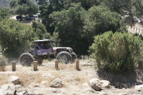 1989 Ford Bronco - A custom-built off-road buggy navigates a challenging course, kicking up dust on a sunny day.