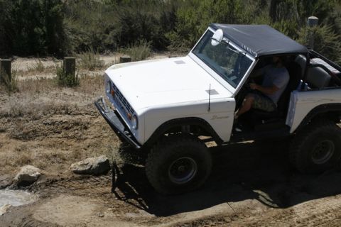 1989 Ford Bronco - A white Ford Bronco navigates a rocky, off-road trail.
