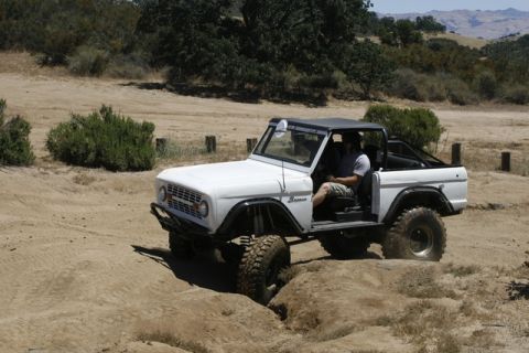 1989 Ford Bronco - A classic Ford Bronco navigates a rough, dusty terrain with a driver inside.