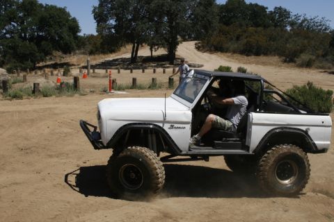 1989 Ford Bronco - A white Ford Bronco is driven off-road on a sunny day.