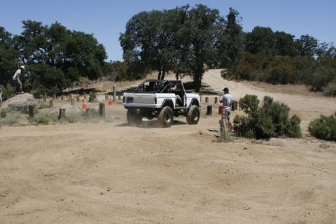 1989 Ford Bronco - A white 1989 Ford Bronco with a roll cage navigates a dusty off-road course.
