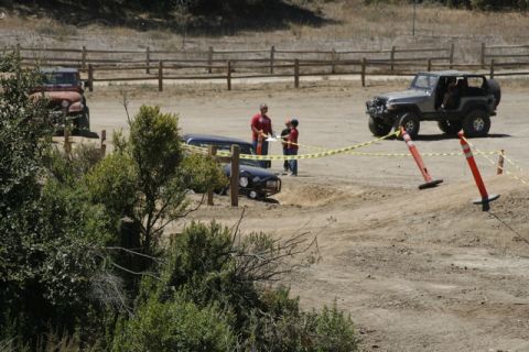 1989 Ford Bronco - Multiple vehicles participate in an off-road event with safety cones and caution tape.