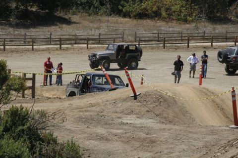 1989 Ford Bronco - Off-road vehicles navigate a challenging dirt course with spectators observing the action.