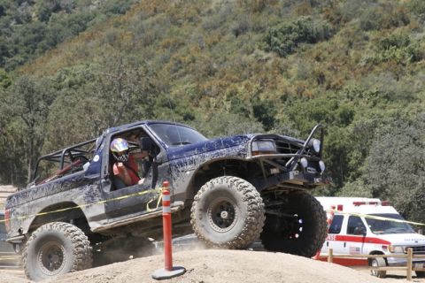 1989 Ford Bronco - Modified blue SUV navigates an off-road course, with an ambulance visible in the background.