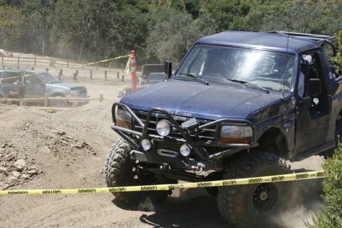 1989 Ford Bronco - This modified truck is navigating a challenging off-road course with caution tape marking the path.