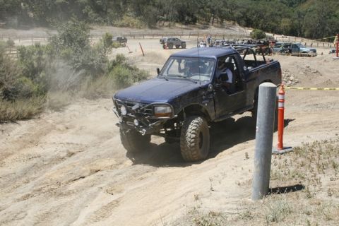 1989 Ford Bronco - This modified SUV navigates a dusty off-road course with other vehicles in the background.