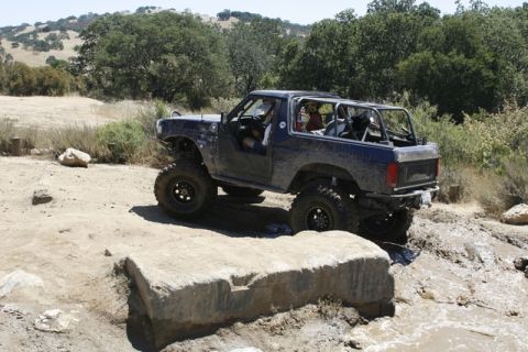 1989 Ford Bronco - This modified SUV navigates a challenging off-road course with a focus on its robust suspension and tire setup.