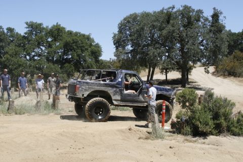 1989 Ford Bronco - A modified Ford Bronco navigates a dusty off-road course with spectators watching.