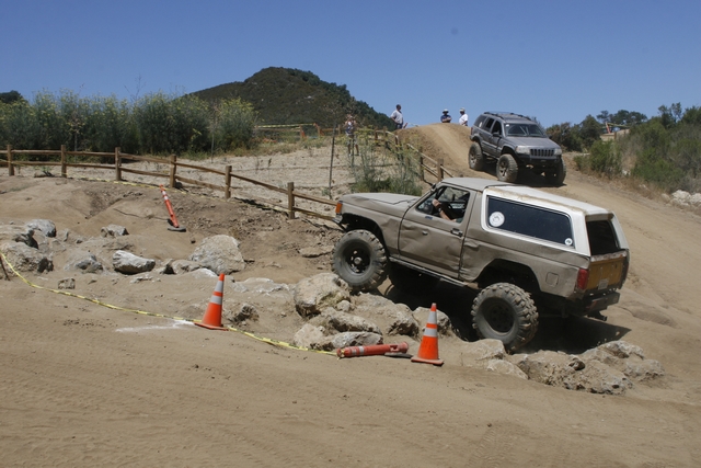 1989 Ford Bronco navigating a rocky off-road course with a Jeep Grand Cherokee behind it