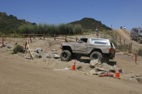1989 Ford Bronco - This modified SUV is tackling a challenging off-road obstacle course with large rocks and steep inclines.
