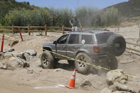 1989 Ford Bronco - A Jeep Grand Cherokee tackles a challenging off-road obstacle course.