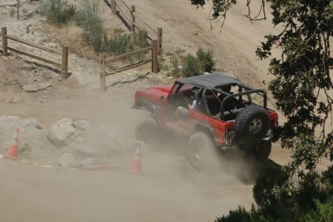 1989 Ford Bronco - This red 1989 Ford Bronco navigates a challenging off-road course, kicking up a cloud of dust as it goes.