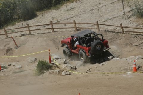1989 Ford Bronco - Red 1989 Ford Bronco navigates a challenging rocky terrain during an off-road event.
