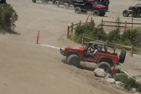 1989 Ford Bronco - A red 1978 Ford Bronco navigates a challenging dirt course with other off-road vehicles in the background.