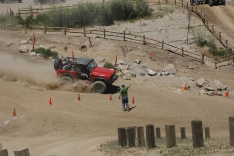 1989 Ford Bronco - A red 1989 Ford Bronco navigates a dusty off-road course, with another vehicle visible in the background.