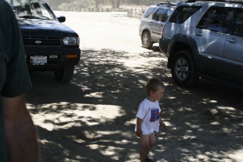 1989 Ford Bronco - A black Nissan Pathfinder is parked in a dirt lot with two other SUVs visible.