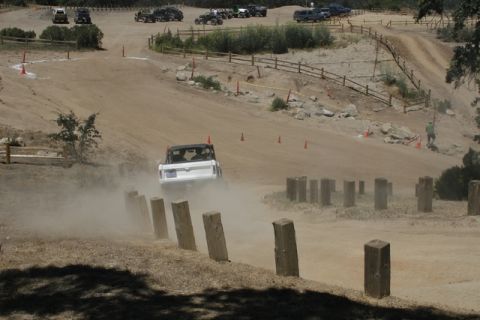 1989 Ford Bronco - A white SUV navigates a dusty off-road course with several other vehicles visible in the distance.