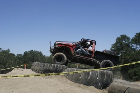 1989 Ford Bronco - A custom-built off-road vehicle tackles a challenging course with large tires and obstacles.