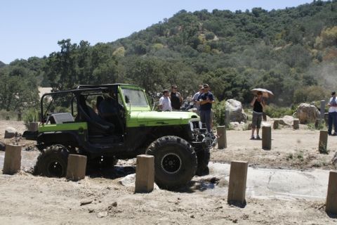 1989 Ford Bronco - A modified Jeep navigates a challenging off-road course with spectators observing the action.