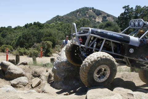 1989 Ford Bronco - Custom off-road buggy tackles a challenging rock obstacle on a sunny day.