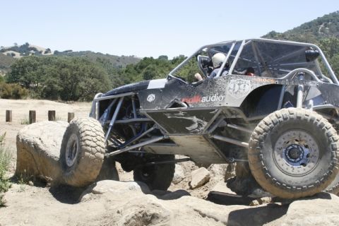 1989 Ford Bronco - This custom off-road buggy navigates a rocky trail with a driver wearing a helmet.