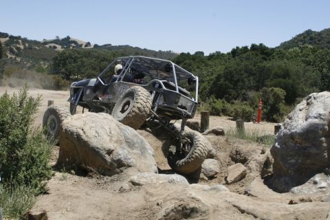 1989 Ford Bronco - A custom off-road buggy navigates a challenging rocky terrain during an event.