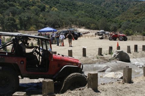 1989 Ford Bronco - Multiple off-road vehicles participate in an event with spectators and tents in the background.