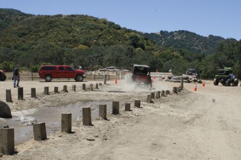 1989 Ford Bronco - Multiple vehicles navigate an off-road course on a sunny day.