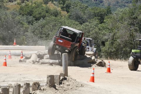 1989 Ford Bronco - Off-road vehicles tackle a challenging obstacle course marked by cones and logs.