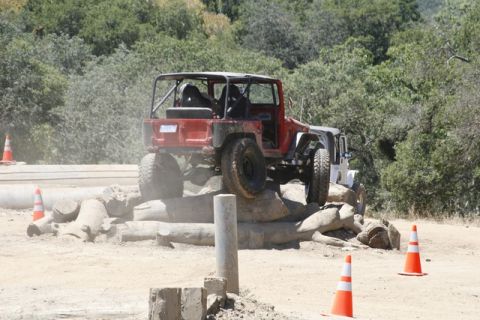 1989 Ford Bronco - An off-road vehicle navigates a challenging obstacle course with logs and rocks.