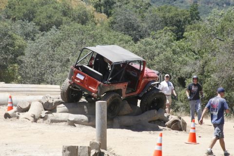 1989 Ford Bronco - An off-road vehicle maneuvers through a challenging obstacle course, with spectators observing the action.