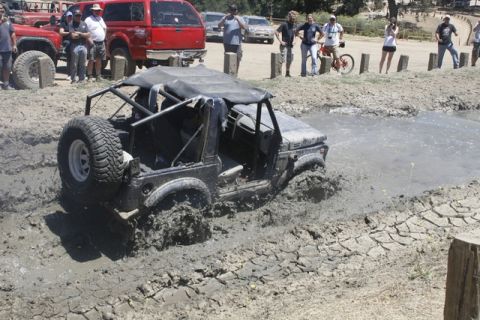 1989 Ford Bronco - Off-road vehicle navigates a challenging mud pit during an event.