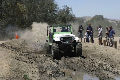 1989 Ford Bronco - An off-road vehicle navigates a muddy track during an event.