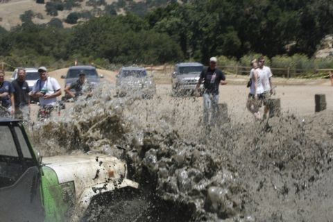 1989 Ford Bronco - Mud flies as off-road vehicles tackle a challenging course, with onlookers observing the action.