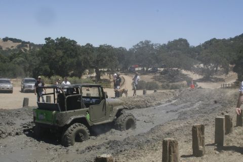 1989 Ford Bronco - Several vehicles are present at a muddy off-road event.