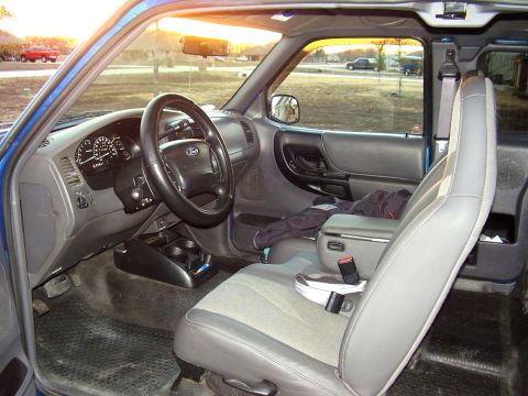 2001 Ford Ranger - The interior of a blue 2001 Ford Ranger is visible from the passenger side, with the dashboard and steering wheel in view.