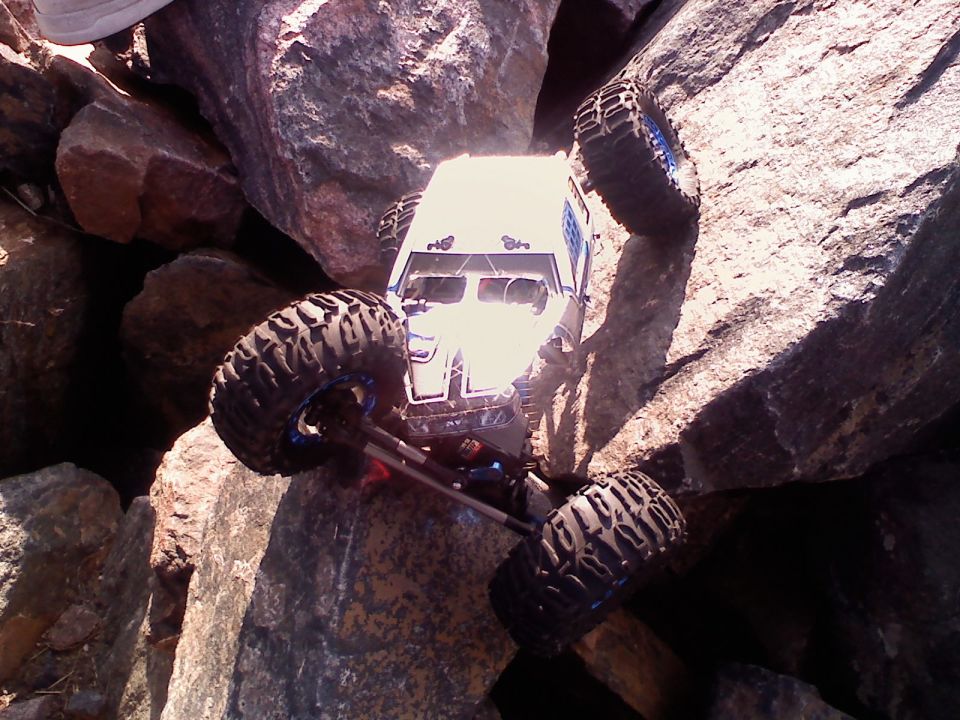 White remote control rock crawler with large tires climbing over rocks