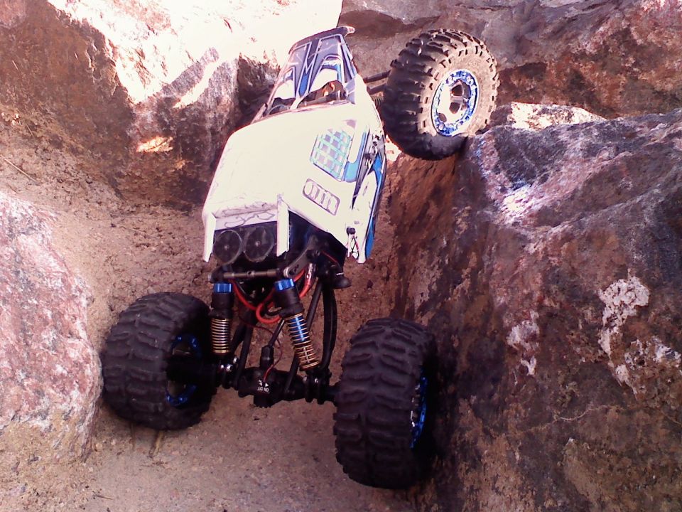 White remote control rock crawler with blue accents climbing a rocky incline