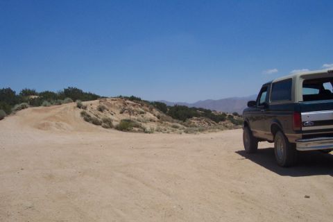 1995 Ford Bronco - This 1995 Ford Bronco is seen from the rear, parked on a dusty, off-road path under a clear blue sky.
