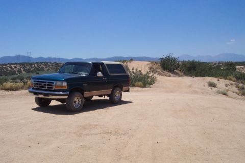 1995 Ford Bronco - A 1995 Ford Bronco sits on a dusty trail under a clear blue sky.
