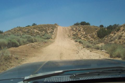 1995 Ford Bronco - Driving up a steep dirt road in a dry, arid landscape.