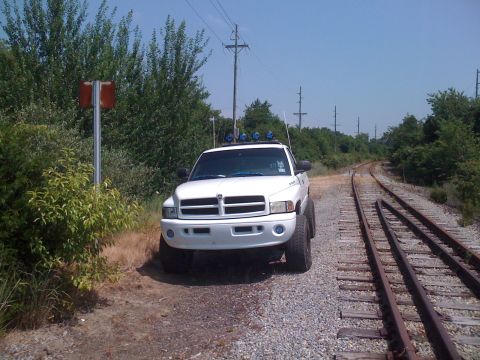 2001 Dodge 1500 - A white Dodge Ram pickup truck is parked beside a set of railroad tracks under a clear blue sky.