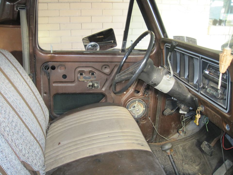 Brown 1979 Ford Bronco interior showing worn seat, dashboard, steering wheel, and door panel