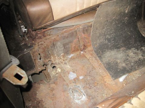1979 Ford Bronco - Extensive rust damage is visible on the interior floor of this vehicle, along with a seatbelt buckle.