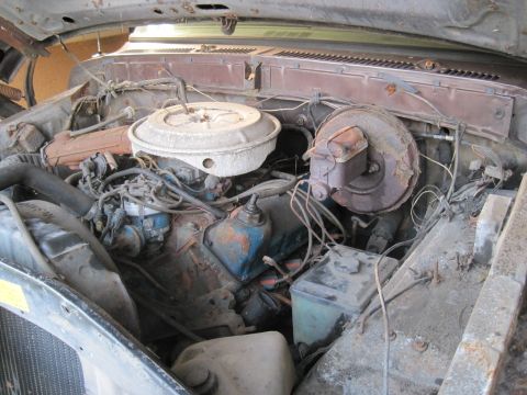 1979 Ford Bronco - The engine bay of an older vehicle shows a V8 engine with its air cleaner assembly and brake booster visible.