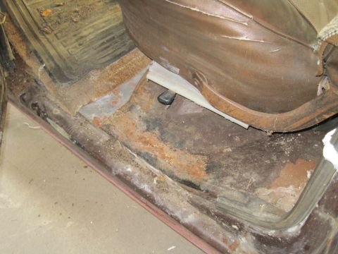 1979 Ford Bronco - The interior of a vehicle shows extensive rust on the floor pan and lower body panels.