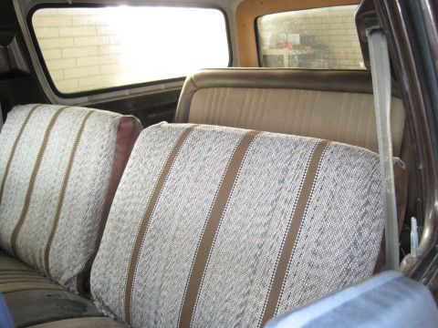 1979 Ford Bronco - The interior of a vehicle shows the rear bench seat with a distinctive striped fabric pattern.