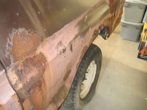 1979 Ford Bronco - The side of a vehicle shows extensive rust damage, with primer visible in some areas.