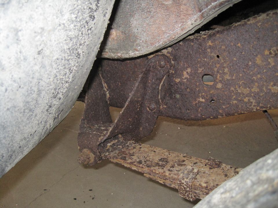 Rusted leaf spring attached to vehicle frame, close-up view